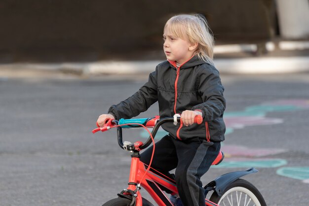 Retrato de menino loiro de bicicleta.