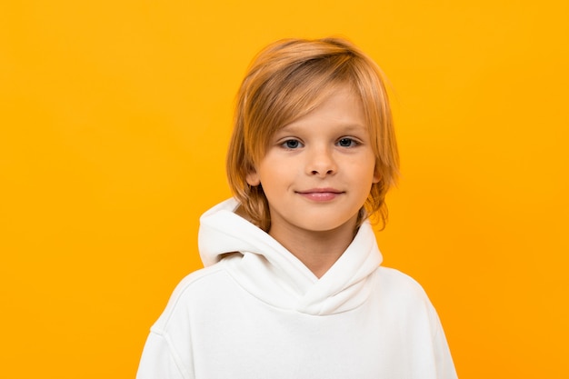 Retrato de menino loiro fazendo careta em close-up amarelo studio