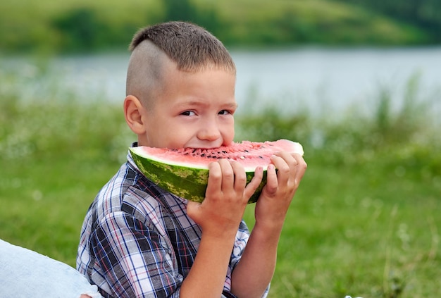 Retrato de menino no piquenique Criança comendo melancia no Prado