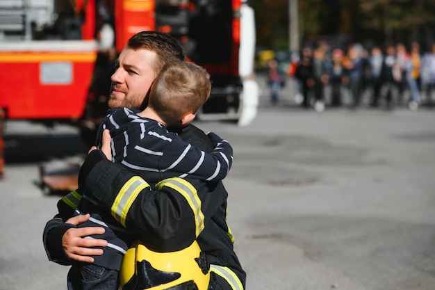 Retrato de menino resgatado com bombeiro em pé perto de caminhão de bombeiros Bombeiro em operação de combate a incêndio