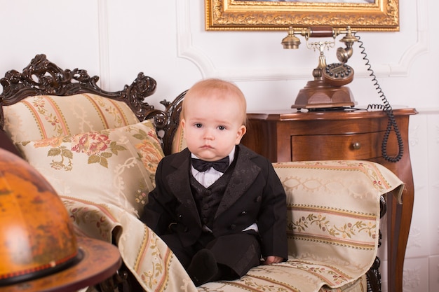 Retrato de menino sentado em uma poltrona