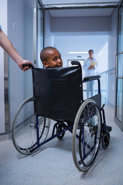 Retrato de menino sentado na cadeira de rodas no corredor