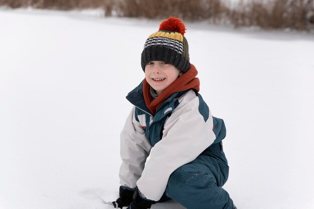 Retrato de menino sorridente com chapéu de malha em fundo de winter park. Férias de inverno.