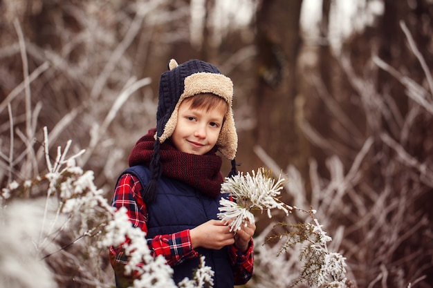 Retrato de menino sorridente em um bosque nevado no inverno