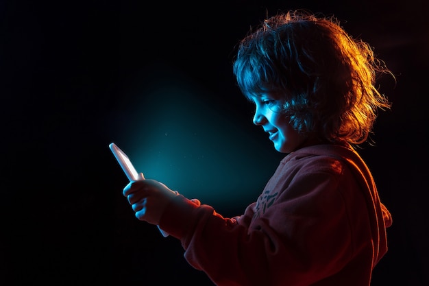 Retrato de meninos caucasianos isolado no fundo escuro do estúdio com luz de néon