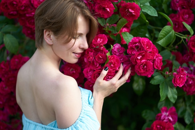 Retrato de moda ao ar livre da bela jovem cercado por rosas.