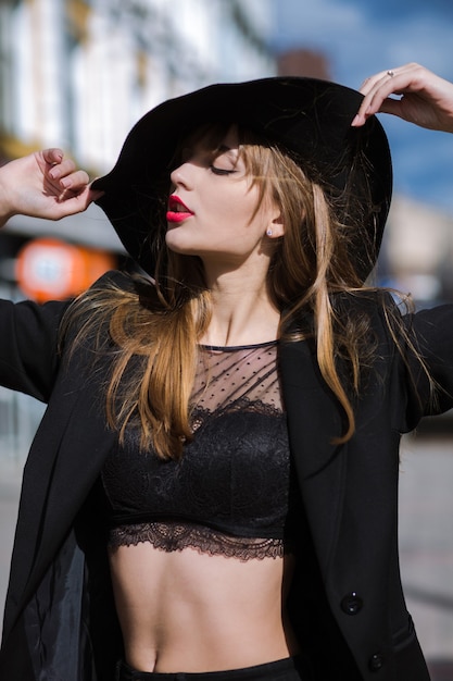 Retrato de moda ao ar livre de uma jovem elegante usando chapéu, lingerie de renda e jaqueta