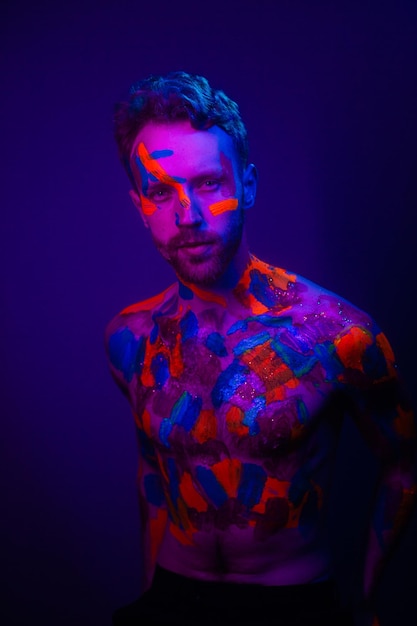 Retrato de moda de um homem com tinta ultravioleta em seu corpo e luz neon no estilo cyberpunk