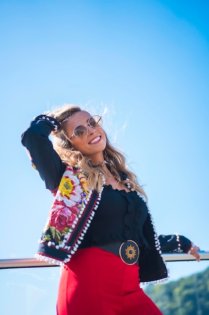 Retrato de moda de uma mulher loira em um terraço com o céu ao fundo