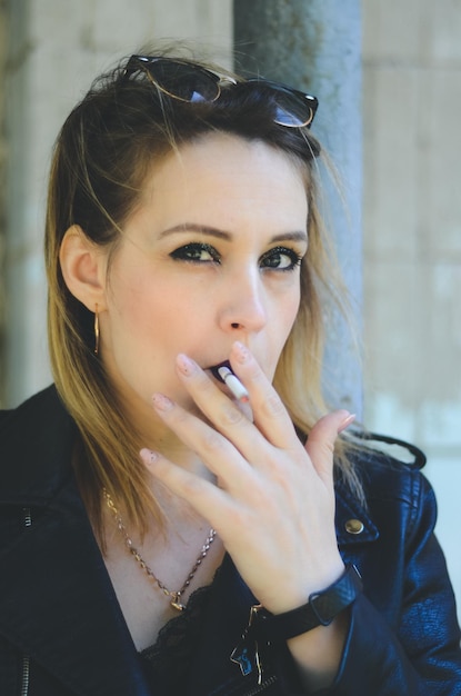 Foto retrato de moda grunge de mulher loira estilosa fuma em jaqueta de couro, humor rock n roll