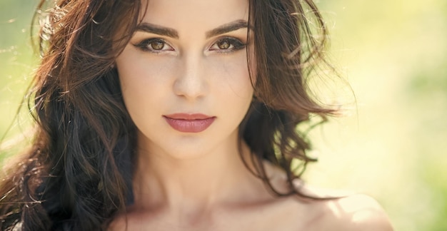 Retrato de moda Rosto de menina com maquiagem na pele jovem na natureza Mulher com longos cabelos morenos em dia ensolarado Conceito de saúde da juventude Skincare Rosto de beleza de moda