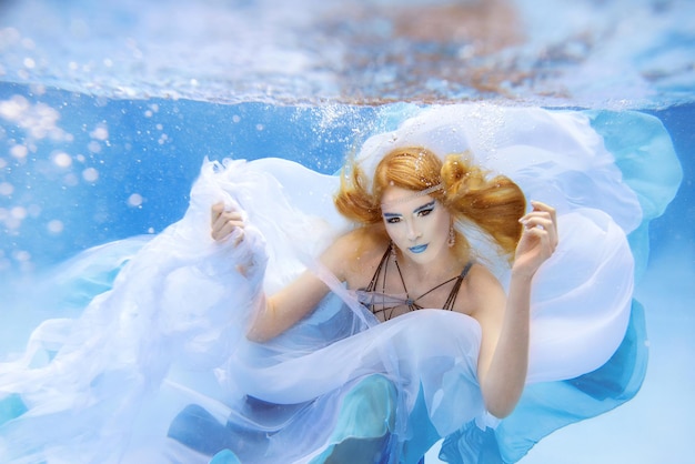 Retrato de moda subaquática de uma bela jovem de vestido azul