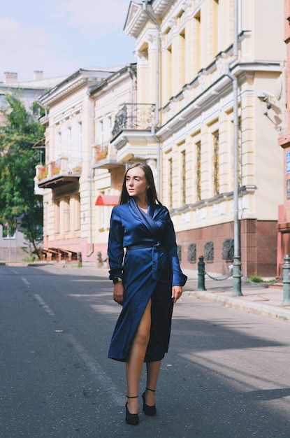 Retrato de moda urbana de uma jovem empresária elegante em um vestido azul longo, com longos cabelos escuros