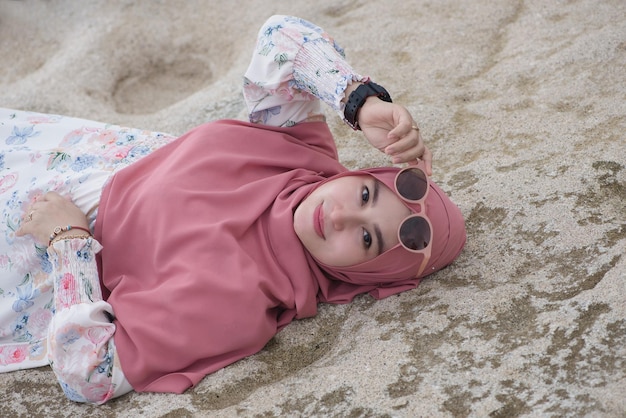 Retrato de modelo asiático hijab deitado na pedra da praia