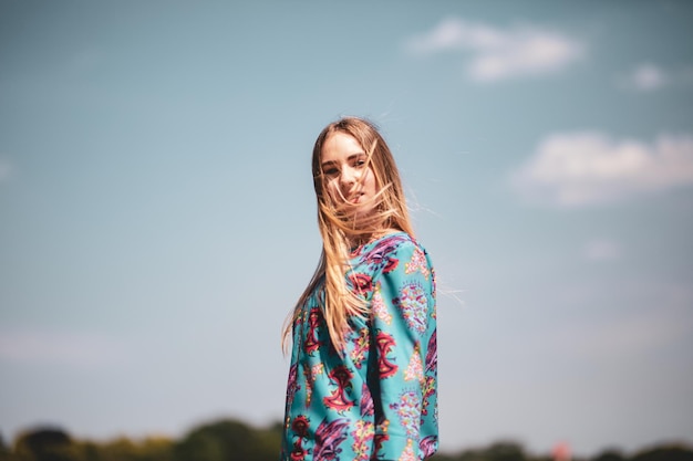 Retrato de modelo feminino com o cabelo desarranjado de pé contra o céu