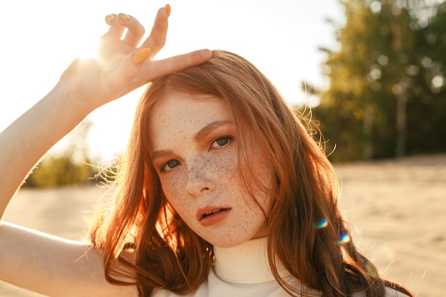 Retrato de modelo feminino sem emoção com longos cabelos vermelhos tocando a cabeça