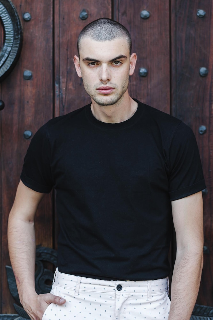 Foto retrato de modelo masculino de pé contra uma porta de madeira