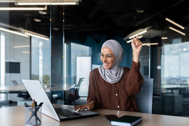 Retrato de muçulmano feliz sorrindo e bem-sucedido no trabalho em uma empresária de escritório com laptop segurando