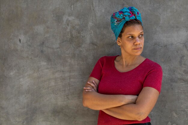 Retrato de mulher 34 afro-americana com lenço na cabeça isolado em fundo cinza com os braços cruzados olha para o lado esquerdo Copiar espaço Oferta de desconto de promoção de conceito