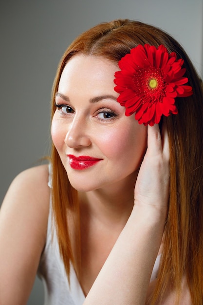 Retrato de mulher adulta com flor vermelha e batom vermelho