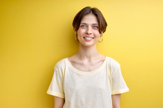 Retrato de mulher adulta fofamente sorrindo posando para a câmera isolada sobre fundo amarelo vestido casu ...