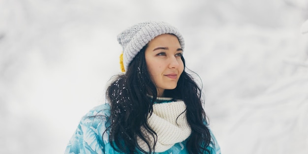 Retrato de mulher adulta jovem em traje de esqui em um fundo de inverno com neve durante as férias ao ar livre