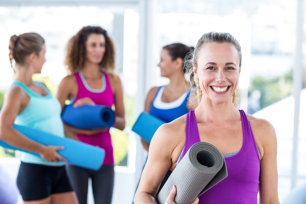 Retrato de mulher alegre segurando tapete de exercícios e sorrindo