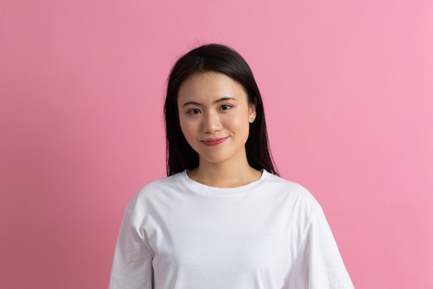 Retrato de mulher americana asiática sorridente em fundo rosa.