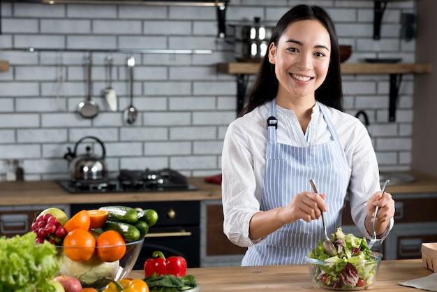 Retrato, de, mulher asian, misturando salada, em, cozinha