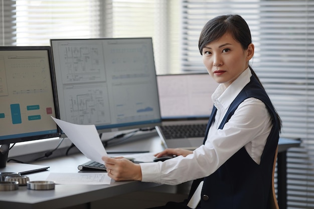 Retrato de mulher asiática como engenheira usando computador no escritório e olhando para o espaço de cópia da câmera