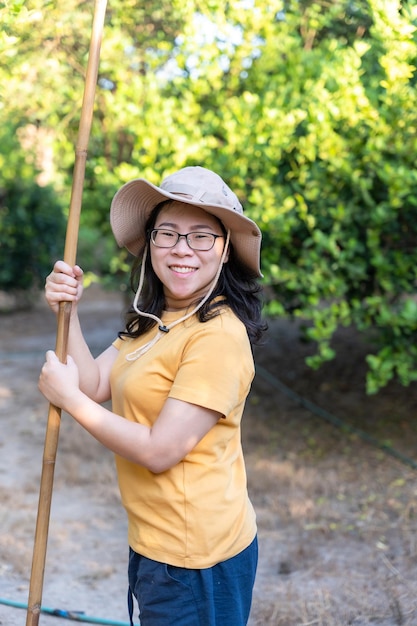 Retrato de mulher asiática sorrindo usa um chapéu colhendo limões verdes no jardim do pomar da fazenda Estilo de vida camponês olhando para a câmera ao ar livre Agricultor e conceito de fazenda de limão orgânico