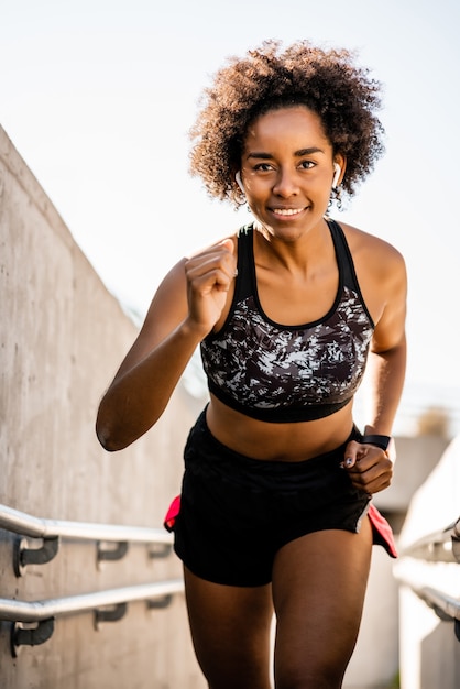 Retrato de mulher atleta afro correndo e fazendo exercício ao ar livre. esporte e estilo de vida saudável.