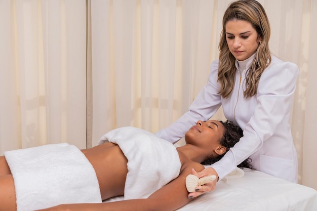 Foto retrato de mulher atraente desfrutando de massagem aromática com pinda nos braços e ombros