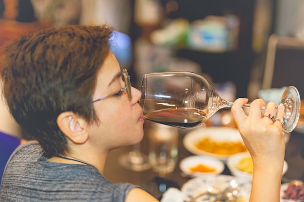 Retrato de mulher bebendo vinho tinto no jantar.