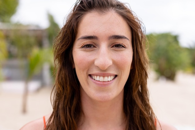 Retrato de mulher birracial feliz olhando para a câmera e sorrindo na praia. Passar tempo de qualidade, estilo de vida, verão e conceito de férias.