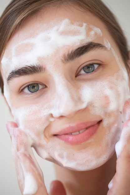 Foto retrato de mulher bonita com a pele clara lavando o rosto com limpador de espuma