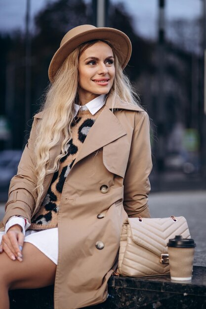 Retrato de mulher bonita com roupa da moda, sentado na escada