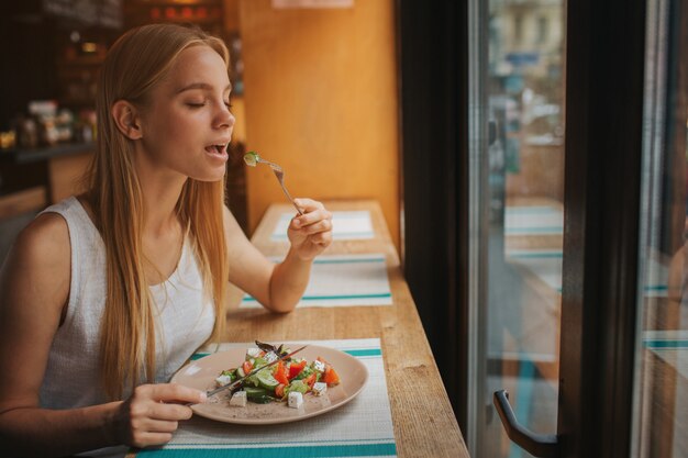 Foto retrato de mulher bonita e sorridente caucasiano comendo salada