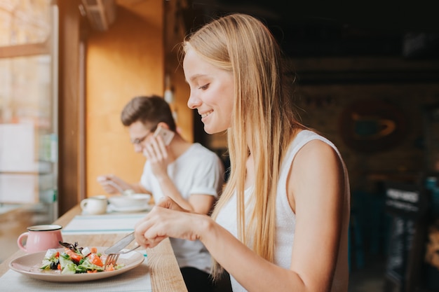 Retrato de mulher bonita e sorridente caucasiano comendo salada