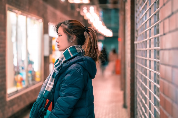 Retrato de mulher bonita em roupas de inverno à noite em um beco em Sendai, Japão