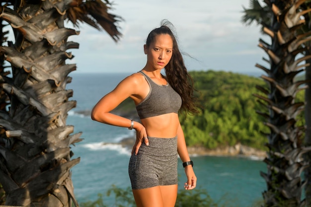 Retrato de mulher bonita em roupas esportivas no pico da montanha à beira-mar Conceito de saúde e viagem