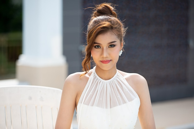 retrato de mulher bonita em vestido branco posado ao ar livre