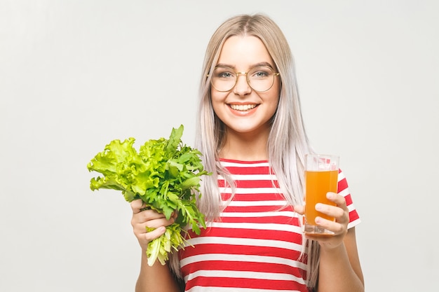 Retrato de mulher bonita feliz com alface e suco de laranja