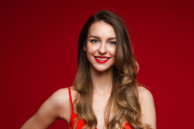 Retrato de mulher bonita feliz com vestido vermelho enquanto posava no estúdio. Conceito de São Valentim