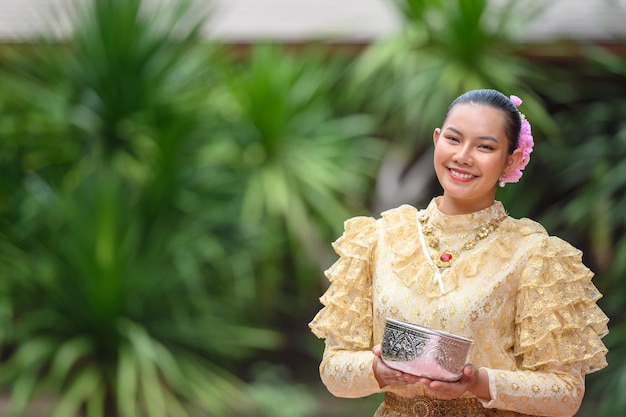 Retrato de mulher bonita no festival Songkran com traje tradicional tailandês no templo segurando tigela de água e sorria a cultura tailandesa com festival de água