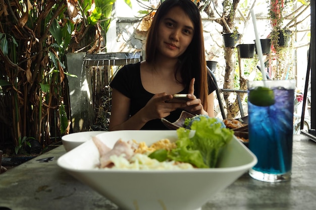 Foto retrato de mulher bonita usando telefone celular com refeição na mesa