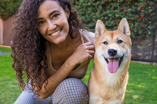 Foto retrato de mulher brincando com cão sentado na grama ao ar livre