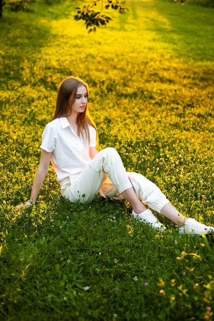 Retrato de mulher calorosa no pôr do sol sentada na grama