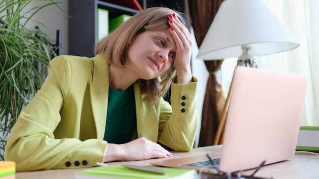 Retrato de mulher cansada trabalhando usando laptop moderno no escritório gerente estressante e exausto