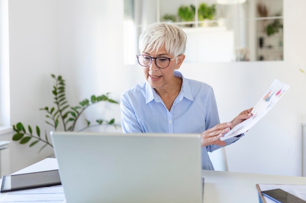 Retrato de mulher casual usando seu laptop enquanto está sentado no escritório em casa e trabalhando Uma atraente empresária de meia idade sentada na frente do laptop e gerenciando sua pequena empresa em casa